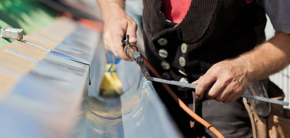 Dachdecker von Meisterdach Fladung bei Spenglerarbeiten an einer Dachrinne