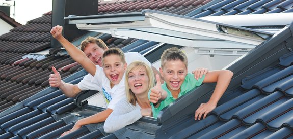 Familie winkt aus ihrem neuen Dachfenster