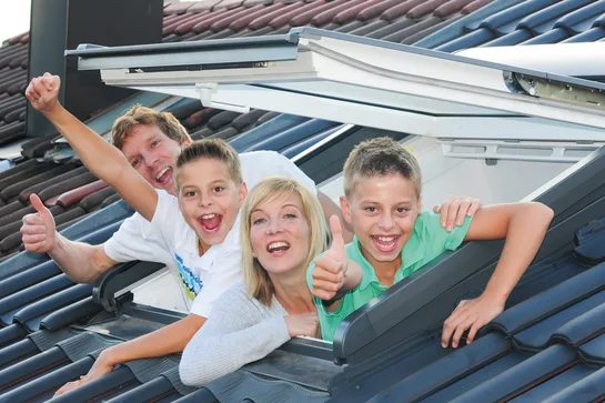 Familie winkt aus ihrem neuen Dachfenster